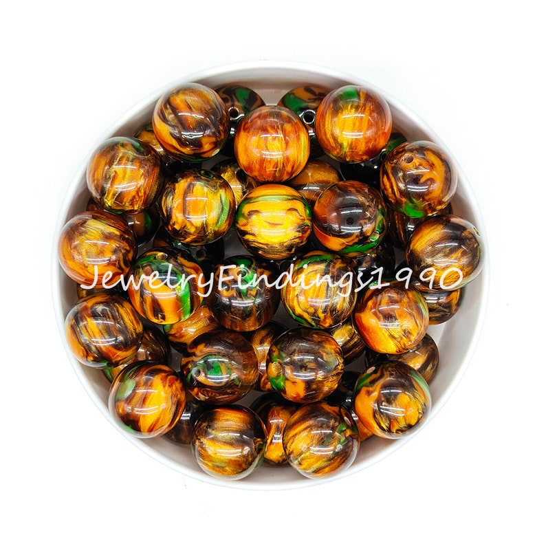 May include: A bowl of round, brown, green, and gold swirled acrylic beads. The beads are approximately 2 cm in diameter.