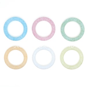 May include: Six colorful, speckled, ring-shaped ornaments. The rings are in shades of blue, pink, green, yellow, white, and light green.