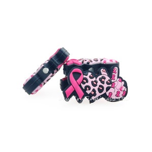 Può includere: Ciondolo in gomma rosa e nero con un nastro rosa e un cuore con stampa leopardata. Il ciondolo ha un retro magnetico.