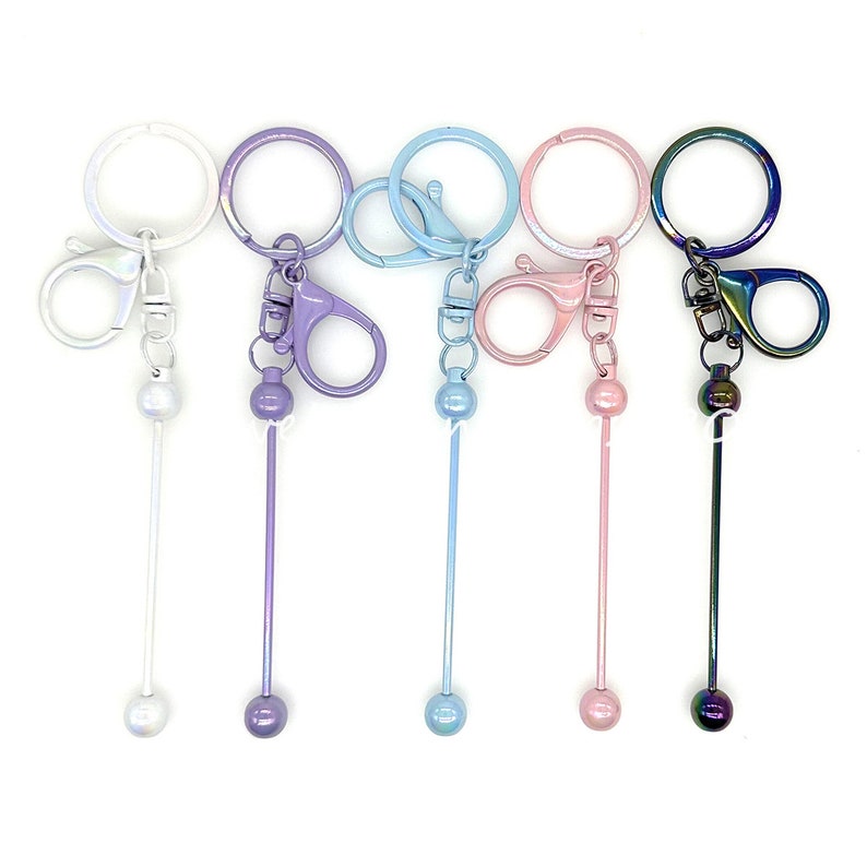 Puede incluir: Cinco llaveros con diferentes anillos met&aacute;licos de colores y una varilla met&aacute;lica larga con una bola en el extremo. Los colores de los llaveros son blanco, morado, azul claro, rosa e iridiscente.