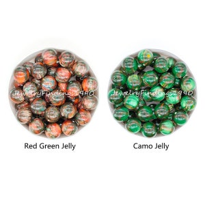 May include: Two bowls of colorful jelly beads. The bowl on the left contains red and green jelly beads. The bowl on the right contains green and brown camo jelly beads.