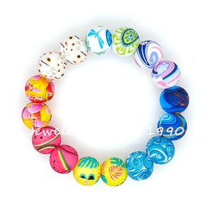 May include: A colorful bracelet made of round beads with various floral and geometric patterns. The beads are in shades of pink, blue, yellow, and white.