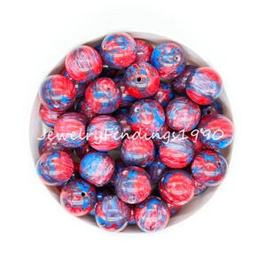May include: A bowl filled with red, blue, and black marbled round beads. The beads are approximately 2 cm in diameter.
