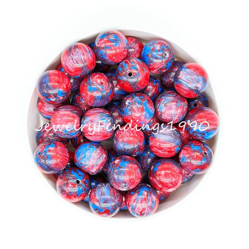 May include: A bowl filled with red, blue, and black marbled round beads. The beads are approximately 2 cm in diameter.