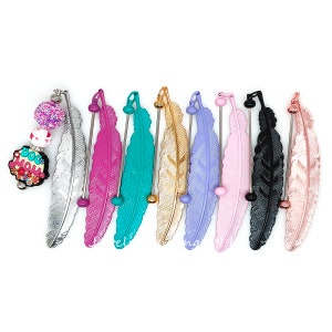 May include: Ten different colored feather bookmarks with a silver, gold, pink, purple, teal, black, and rose gold finish. Each bookmark has a small bead at the top and a metal rod that runs through the feather.