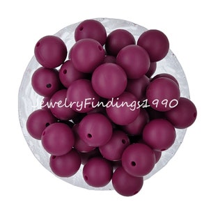 May include: A bowl filled with 25 round, dark purple silicone beads. The beads are approximately 2 cm in diameter and have a smooth, matte finish.