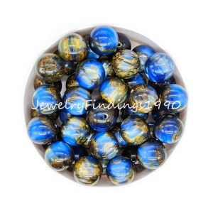 May include: A bowl of blue and gold swirl acrylic beads. The beads are round and have a glossy finish.