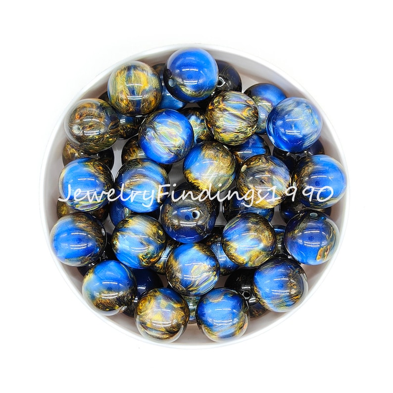 May include: A bowl of blue and gold swirl acrylic beads. The beads are round and have a glossy finish.