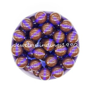May include: A bowl of brown and purple round beads. The beads have a glossy finish and a purple stripe around the middle.