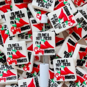 May include: A collection of white square beads with the text "I'm not a hot mess, I'm a spicy disaster" and a red chili pepper design. The beads are scattered, with a white bottle stopper in the center.