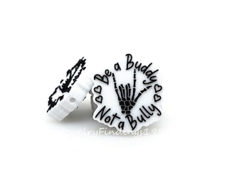 May include: White silicone charm with a black skeleton hand making the 'I love you' sign language gesture. The charm has the text 'Be a Buddy Not a Bully' around the hand.