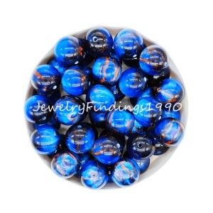 May include: A bowl of blue and orange swirl glass beads. The beads are round and have a glossy finish.