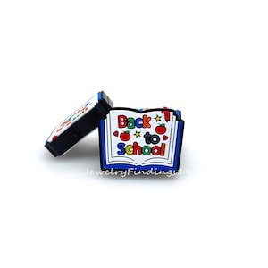 May include: A colorful book charm with the words "Back to School" and red apples. The charm is made of silicone and is perfect for adding a fun touch to your shoes or bag.