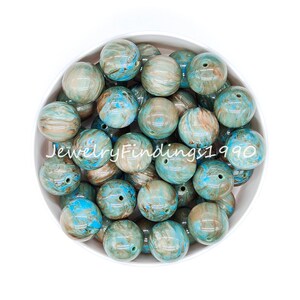 May include: A bowl of 20 round, blue and brown marbled plastic beads. The beads are approximately 2 cm in diameter.