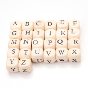 May include: Wooden alphabet blocks, each with a letter from A to Z printed in black. The blocks are arranged in rows and columns, perfect for educational games or decorative purposes.