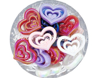 May include: A bowl of colorful, iridescent heart-shaped charms. The charms are made of plastic and have a layered, multi-dimensional design. They are perfect for adding a touch of whimsy to jewelry or crafts.