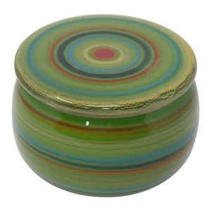Könnte beinhalten: Eine grüne Keramik-Butterdose mit Deckel. Der Deckel hat ein konzentrisches Kreisdesign in Grün-, Blau-, Rot- und Gelbtönen. Die Dose hat ein gestreiftes Design in Grün-, Blau-, Rot- und Gelbtönen.