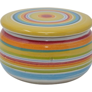 Könnte beinhalten: Ein Keramiktopf mit Deckel, verziert mit horizontalen Streifen in Gelb, Rot, Orange, Grün und Blau. Der Deckel hat ein konzentrisches Kreisdesign. Der Topf ist rund und hat einen weißen Sockel.