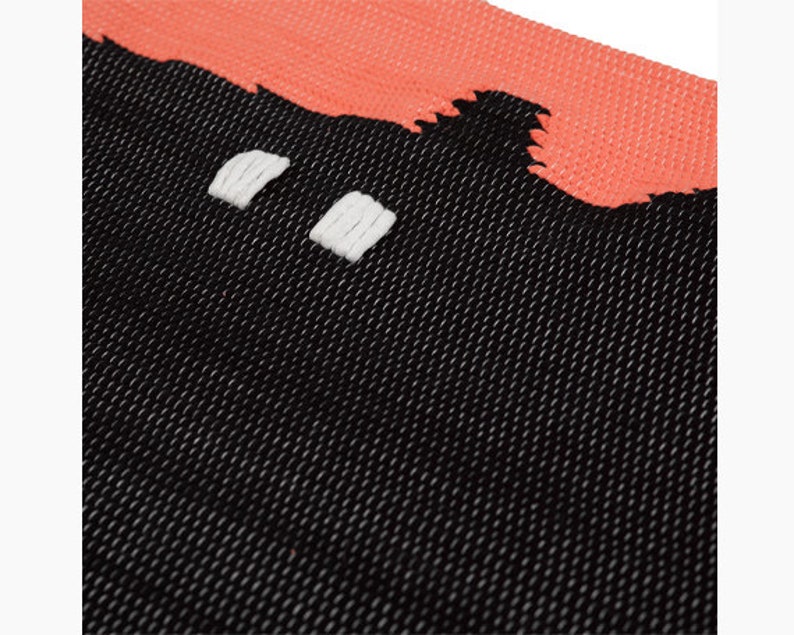 May include: Black and coral woven rug with a geometric pattern. The rug has a textured surface and is made of a soft, durable material.