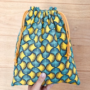 Peut inclure: Un sac à cordon bleu et jaune avec un motif géométrique. Le sac est en tissu et a un cordon de serrage jaune.
