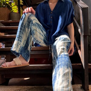 Model wearing indigo wide-leg cotton pants with elastic drawstring waist with an indigo relaxed fit buttoned up shirt sitting on stairs