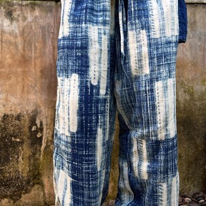 May include: Loose-fitting, wide-leg pants in a blue and white patterned design. The pants feature a tie waist and a textured, woven fabric. The top is a matching blue, creating a coordinated outfit. The overall style is casual and comfortable.