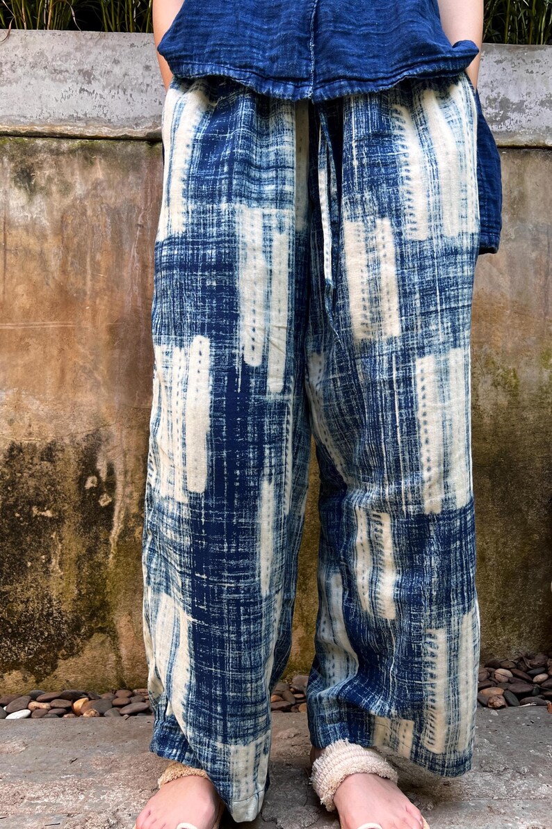 May include: Loose-fitting, wide-leg pants in a blue and white patterned design. The pants feature a tie waist and a textured, woven fabric. The top is a matching blue, creating a coordinated outfit. The overall style is casual and comfortable.
