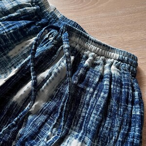 Macro shot of the Still Waters Pants in Ink Shibori, airy double-gauze cotton fabric in indigo, showing weave and hand-dyed variations.