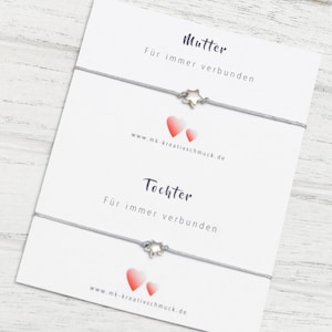 Könnte beinhalten: Zwei graue Armbänder aus Kordel mit silbernen Stern-Anhängern. Jedes Armband hat eine Karte mit dem Text "Mutter" oder "Tochter" und dem Spruch "Für immer verbunden". Die Karten enthalten auch die Website-Adresse "www.mk-kreativschmuck.de".