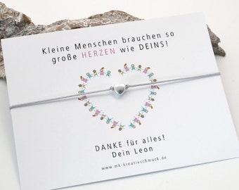 May include: A white card with the text "Kleine Menschen brauchen so große HERZEN wie DEINS!" and "DANKE für alles! Dein Leon www.mk-kreativschmuck.de". A grey string bracelet with a silver heart charm is attached to the card.