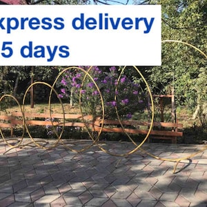 May include: A set of five gold metal hoops arranged in a cascading design. The hoops are used for wedding or event decor. Express delivery 3-5 days.