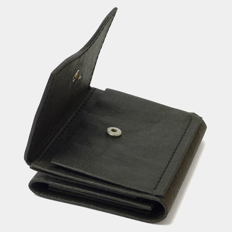 May include: A black leather wallet with a fold-over flap and a snap closure. The wallet is open and has multiple compartments.