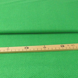 Op de afbeelding: Groene stof met een wit stippenpatroon. De stof wordt gemeten met een liniaal die 50 cm aangeeft.