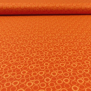 Könnte beinhalten: Orangener Stoff mit einem weißen Kreis-Muster. Der Stoff ist in der Hälfte gefaltet.