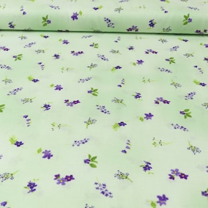 Könnte beinhalten: Ein hellgrüner Stoff mit einem sich wiederholenden Muster aus kleinen lila Blüten. Der Stoff ist glatt und hat eine weiche Textur.