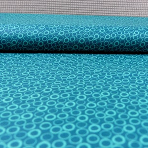 Könnte beinhalten: Tealfarbener Stoff mit einem weißen Kreis-Muster. Der Stoff ist in der Mitte gefaltet.