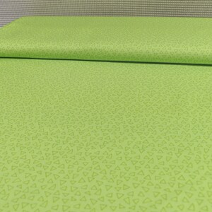 以下が含まれることがあります： 薄い緑色の小さな三角形が繰り返しパターンになっている緑色の生地です。