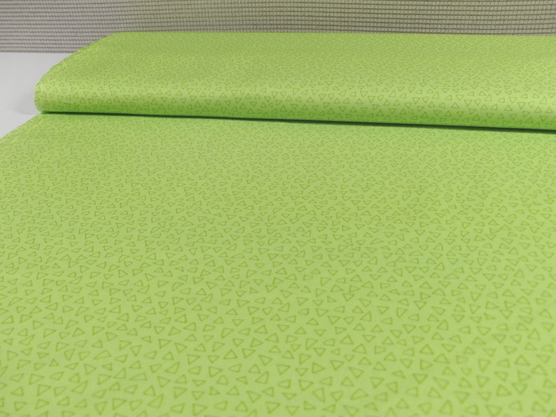 以下が含まれることがあります： 薄い緑色の小さな三角形が繰り返しパターンになっている緑色の生地です。