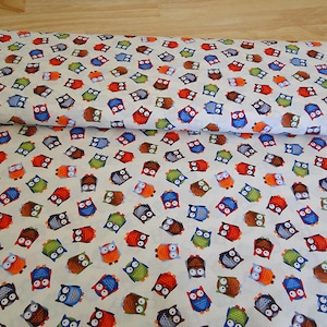 Könnte beinhalten: Weißer Stoff mit einem sich wiederholenden Muster aus bunten Eulen. Die Eulen sind in verschiedenen Blautönen, Grün-, Rot-, Braun- und Grautönen.