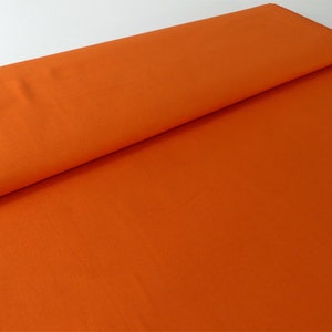 Könnte beinhalten: Nahaufnahme eines leuchtend orangefarbenen Stoffes. Der Stoff ist glatt und hat einen leichten Glanz.