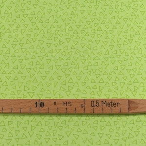 以下が含まれることがあります： 白い三角形の模様がついた緑色の布。布の上に「0.5メートル」と書かれた木製の定規が置かれている。