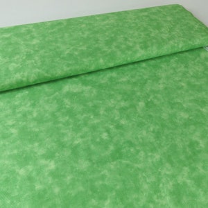 Könnte beinhalten: Grüner Stoff mit einem marmorierten oder Batik-Muster. Der Stoff hat einen hellgrünen Hintergrund mit dunkleren grünen Wirbeln und Streifen.