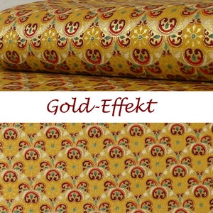 Op de afbeelding: Gouden stof met een herhalend patroon van gestileerde bloemen en bladeren. De stof heeft een subtiele glans.