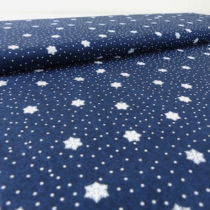 Könnte beinhalten: Marineblauer Stoff mit einem weißen Schneeflockenmuster. Der Stoff hat eine dezente Textur und ein sich wiederholendes Muster aus Schneeflocken und kleinen weißen Punkten.
