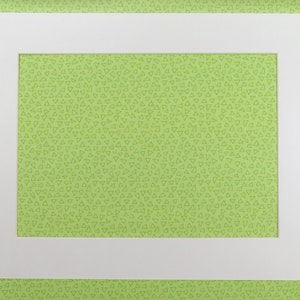以下が含まれることがあります： 緑色の背景に白いマット。マットの中央に長方形の開口部があります。