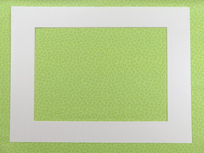 以下が含まれることがあります： 緑色の背景に白いマット。マットの中央に長方形の開口部があります。