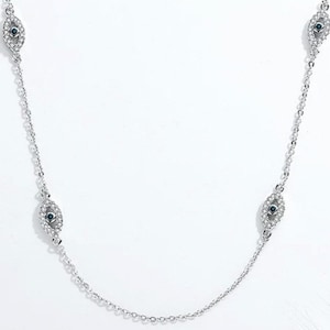 May include: A silver-toned chain necklace featuring multiple eye-shaped charms. Each charm is encrusted with small clear stones and centers on a single dark blue stone. The delicate metal chain connects these symmetrical motifs in a repeating pattern.