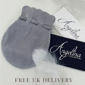 May include: A grey suede-like drawstring pouch with a scalloped top edge, accompanied by a white feather and two rectangular cards featuring the text Angelina Collection in a script font, one white and one dark blue.