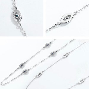 May include: A silver-toned chain bracelet featuring multiple eye-shaped charms. Some charms are encrusted with small clear stones and a central dark blue stone, while others are smooth silver metal with a dark center detail.