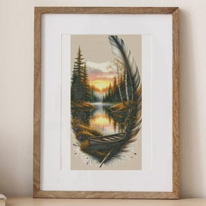 Peut inclure: Tableau encadré représentant un paysage serein avec un lac, des arbres et un coucher de soleil. L'image est encadrée par une forme de plume. L'œuvre est posée sur une table en bois avec des livres et une tasse en céramique.